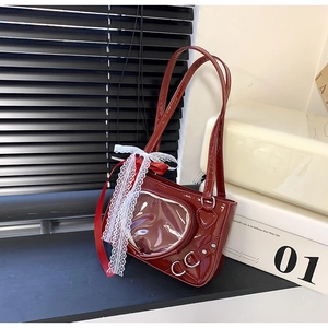 Detail of burgundy patent leather bag featuring a heart window and lace bow accent