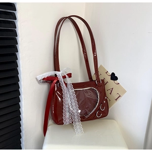 Detail of dark red patent leather heart-shaped window bag with lace and silk bow