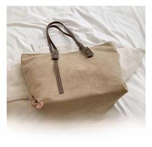 Detail showing matte texture and brown strap of the large khaki tote bag on white bedding