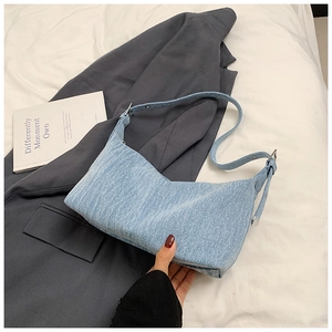 Close-up of light blue denim fabric texture and adjustable silver buckle on shoulder bag