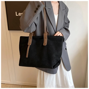 Detail of minimalist large black tote bag with brown leather straps for work use
