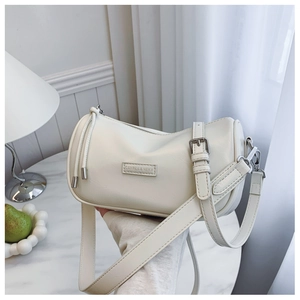 Detailed close-up of cream textured leather shoulder bag with wide strap and silver buckle