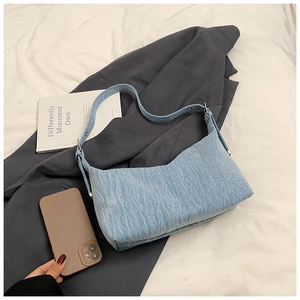 Detail of blue denim shoulder bag showing twill texture and silver adjustable buckle
