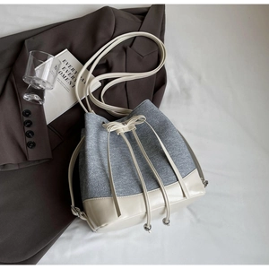 Detail of grey canvas bucket bag featuring cream PU leather trim and drawstring closure