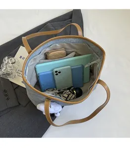 Spacious interior of a grey denim tote bag showing gadgets like tablets and umbrella