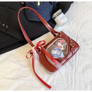 Detail of red patent leather heart-shaped window bag with badges and lace bow