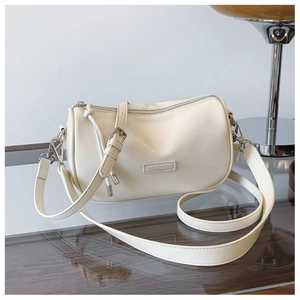 Detailed close-up of cream cylindrical crossbody bag with silver hardware and logo