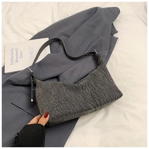 Detail of grey denim texture and shoulder strap on a minimalist dumpling bag