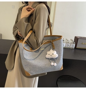 Detail of grey canvas tote bag with brown leather trim and cute white plush charm