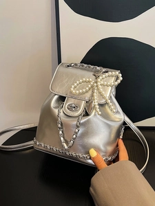 Metallic silver bucket backpack with chain strap and pearl bow charm in urban style