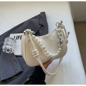 Detail of cream leather baguette bag with pearl chain and silver heart link decorations