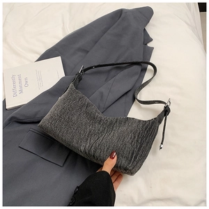 Detail of grey textured denim shoulder bag with adjustable black leather strap and silver buckle