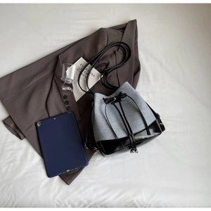 Close-up of color-block bucket bag showing grey felt and black leather stitching detail