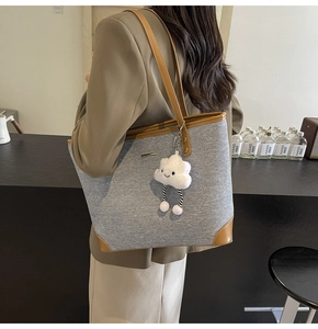 Detail of grey canvas tote bag with brown leather trim and cute white cloud pendant