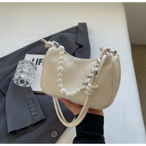 Detail of cream white handbag with pearl handle and silver heart chain on gray suit