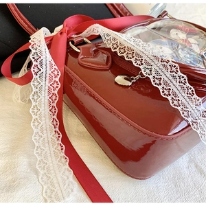 Close-up of red patent leather ita bag with heart zipper and clear display window