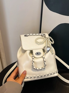 Glossy cream faux leather backpack with silver chain handle and pearl bow charm detail