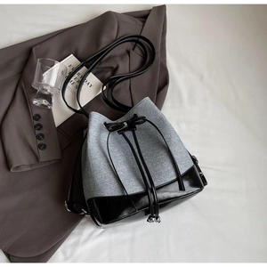 Detail of color-block bucket bag showing grey tweed and black patent leather texture