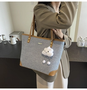 Detailed view of grey canvas tote bag with brown leather trim and cute cloud charm