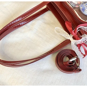 Detail of red patent leather ita bag featuring lace bows and anime badge display