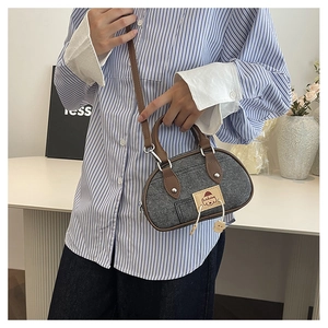 Dettaglio mini borsa in denim grigio con finiture in pelle marrone e ciondolo a orso