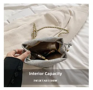 Detail view of spacious interior of grey drawstring bucket bag with gold chain strap