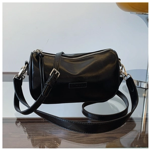 Detailed view of black cylindrical pillow bag with silver hardware and logo embossing