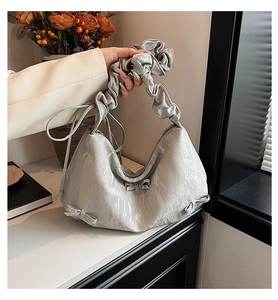 Détail du sac à bandoulière argenté plissé avec nœud et poignée à volants