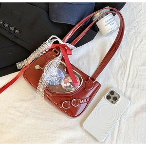 Detail of burgundy patent leather ita-bag featuring transparent window and lace bows