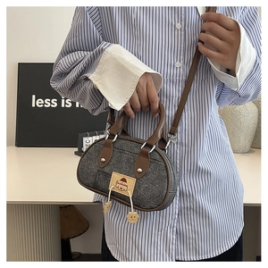 Dettaglio della mini borsa a bauletto in denim con manici in pelle e ciondoli