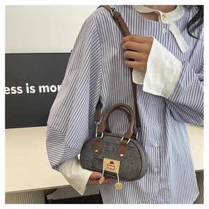 Dettaglio della borsa a bauletto in denim vintage con manici in pelle marrone e patch moda