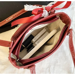 Interior detail of red glossy bag showing three compartments and a zipper pocket