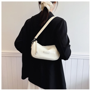 Detailed back view of a beige leather shoulder bag with wide strap on a model