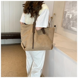 Detail view of khaki canvas tote bag with brown leather handles and spacious interior