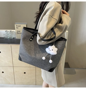 Detail of grey felt tote bag featuring black leather trim and white cloud plush charm