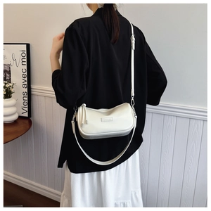 Detail of white leather shoulder bag with adjustable strap and silver-tone hardware accents