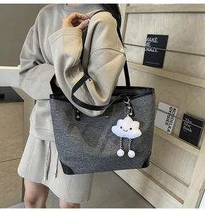 Macro detail of dark grey felt tote bag with black faux leather trim and cloud charm