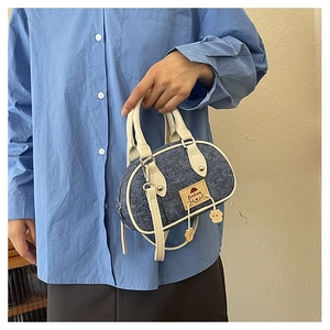 Dettaglio della borsa in denim a contrasto con tessuto blu e finiture bianche
