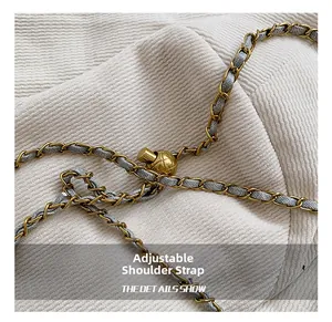 Detail of grey fabric woven gold chain strap with adjustable quilted metal ball