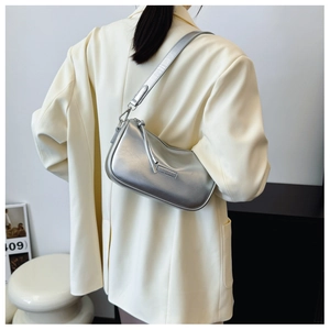 Detail showing the shiny metallic silver texture and side knot zipper of the shoulder bag