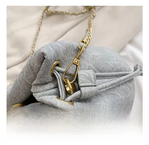 Close-up of gray textured canvas bucket bag with gold chain and premium metal hooks