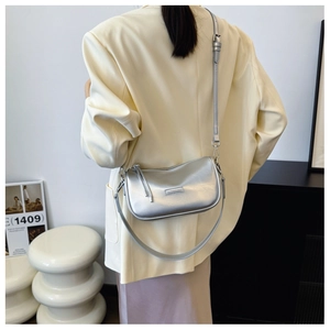 Detail of silver metallic shoulder bag showing adjustable strap and textured finish