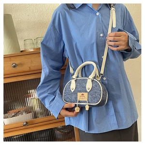 Dettaglio della borsa denim blu con finiture in pelle bianca e toppa a cartone animato
