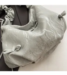 Détail du sac plissé gris montrant la texture du tissu métallique et le nœud