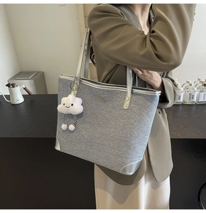 Detail of gray denim tote bag with silver leather handles and white cloud plush charm