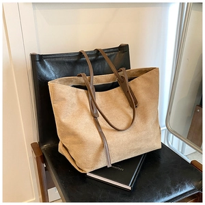 Close-up of a large khaki canvas tote bag with brown leather handles on a chair