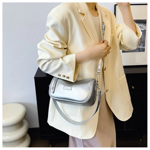 Detail of silver metallic cylinder bag with logo plate and sleek silver hardware