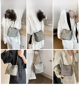 Detail shot of grey crackle texture bucket bag with bronze chain strap on a model