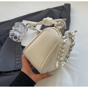 Detail of cream white PU handbag featuring pearl chain and knotted handle design