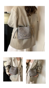 Detail view of grey drawstring bucket bag with gold chain strap and crackle texture